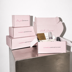 Set of pink boxes with skincare products on a metallic surface